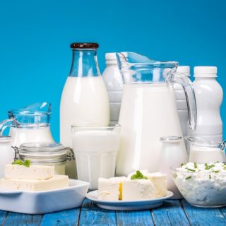 Dairy products on painted wooden table over blue background