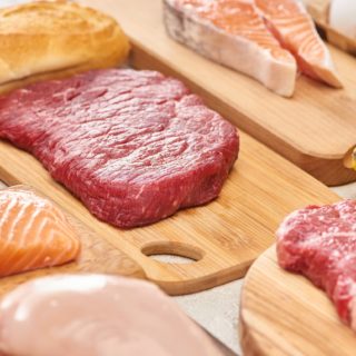 Fresh Raw Meat, Fish, Poultry on Wooden Cutting Boards Near Apple, Lemon, Baguette And Eggs